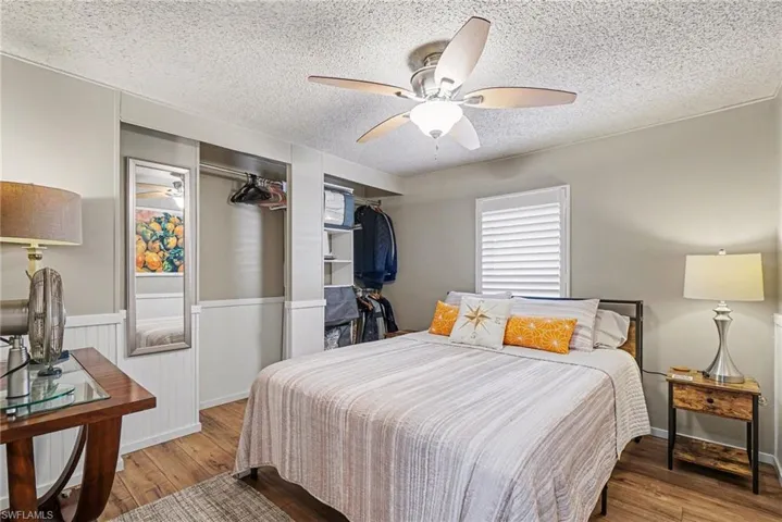 Bedroom featuring a closet, a textured ceiling, wood-type flooring, and ceiling fan.