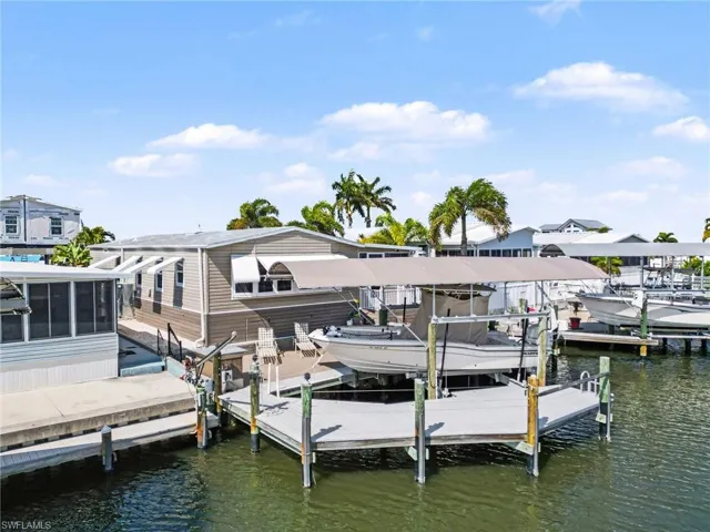Dock area featuring boat lift, a water view, and a sunroom