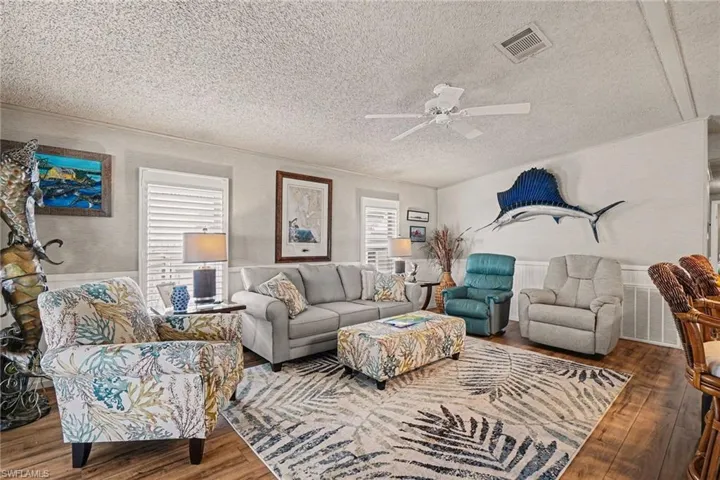 Living room ceiling fan, a textured ceiling, and wood finished floors