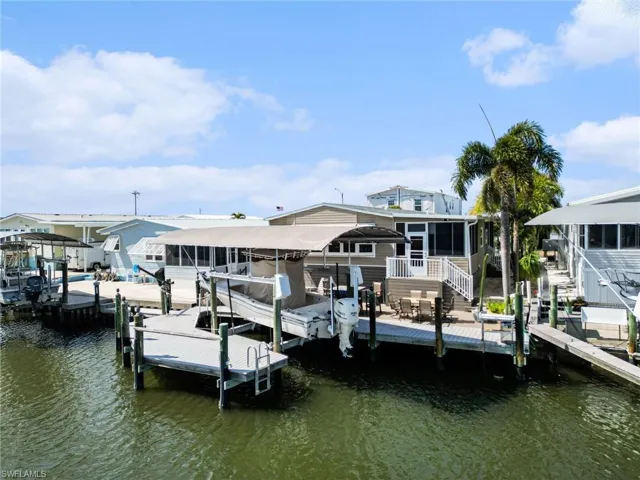 Dock area with boat lift, a water view, and a sunroom