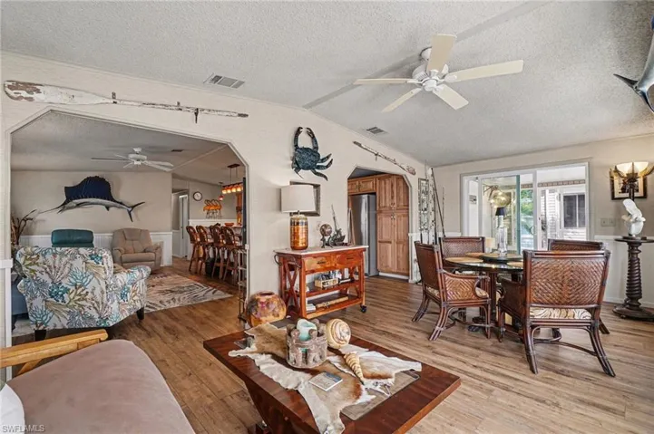Living area with ceiling fan, arched walkways, and hardwood / wood-style floors