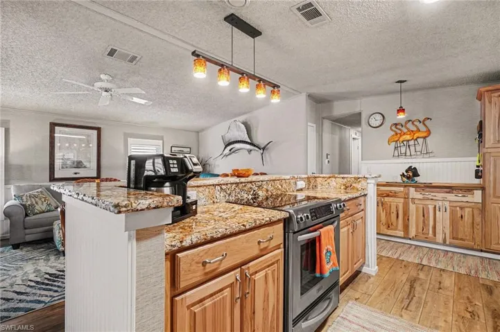 Kitchen with stainless steel electric stove, light wood-style floors, & open floor plan.