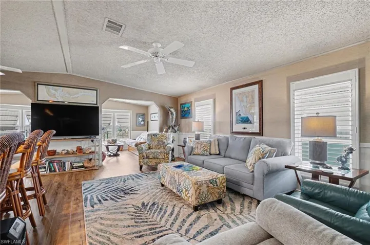Living room with arched walkways, hardwood / wood-style flooring, and  ceiling fan