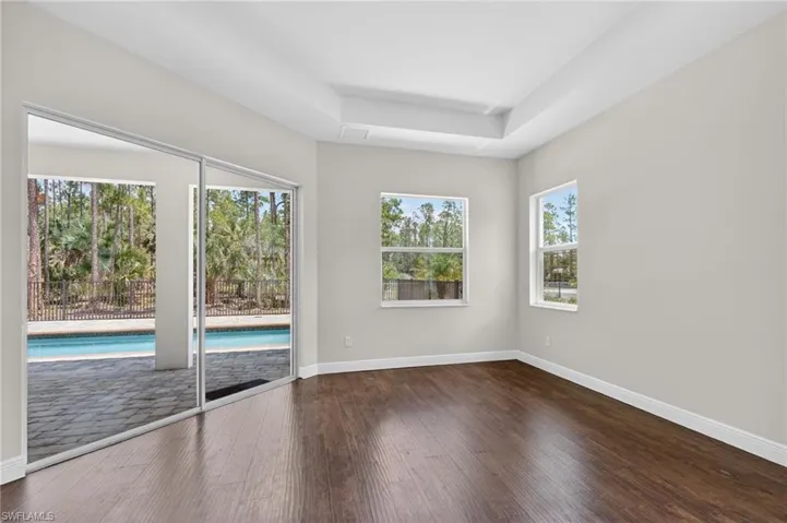 Primary bedroom with tray ceiling and sliders to outdoor area and Pool