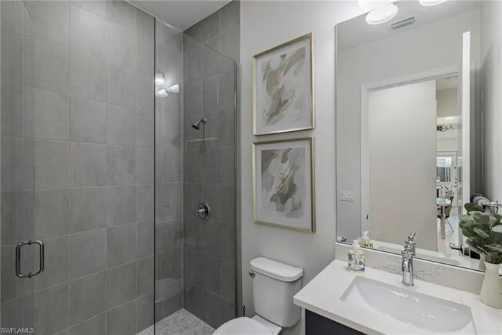Bathroom with a shower with door, toilet, and vanity