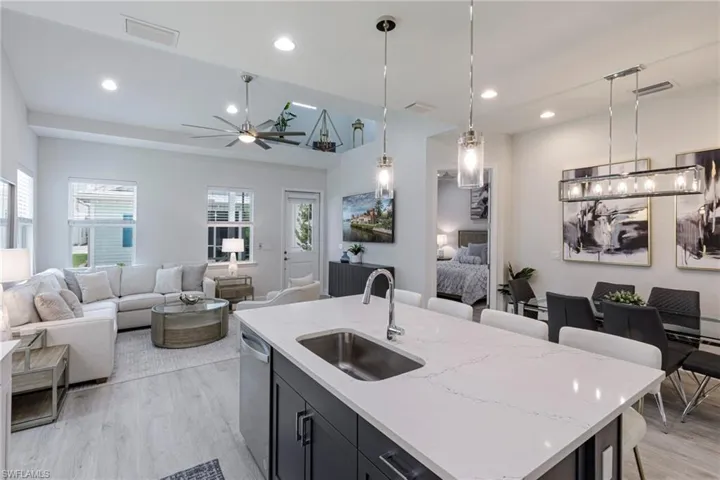 Kitchen with ceiling fan, sink, light hardwood / wood-style flooring, and a kitchen island with sink