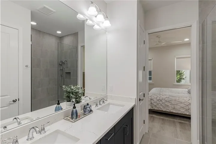 Bathroom featuring hardwood / wood-style flooring, double sink vanity, a shower with door, and ceiling fan