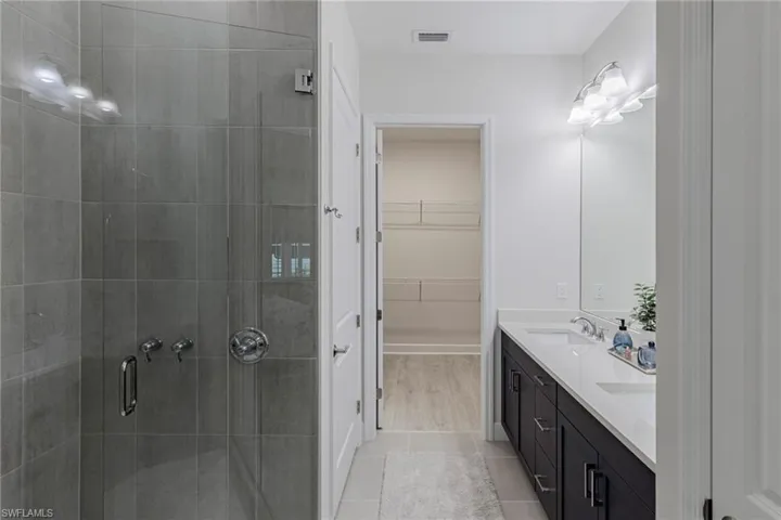 Bathroom featuring dual vanity, a shower with door, and wood-type flooring