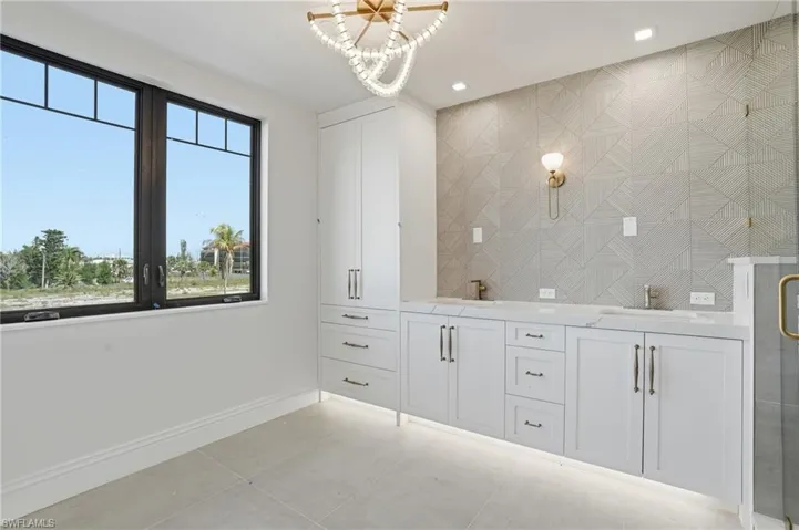 Bathroom with double vanity, hanging lights, a stall shower, and light tile patterned floors