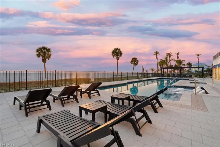 Pool at dusk featuring a patio and a community pool