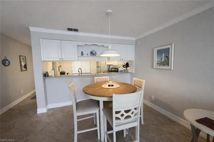 Dining space with crown molding and light tile patterned floors
