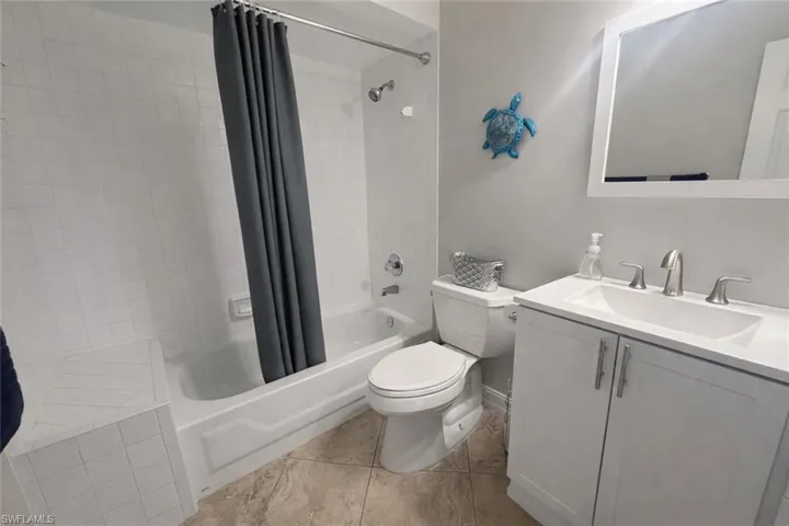 Bathroom with vanity, shower / bath combination with curtain, and light tile patterned floors