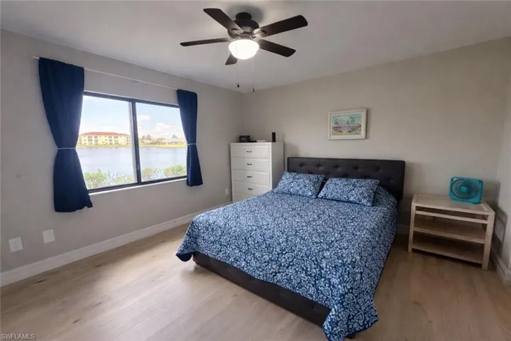 Bedroom featuring light wood finished floors, a water view, and ceiling fan