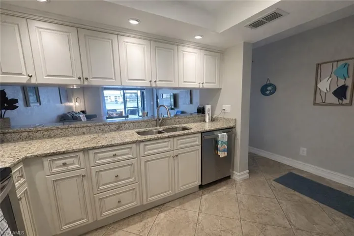 Kitchen with light stone countertops, stainless steel appliances, recessed lighting, and white cabinetry