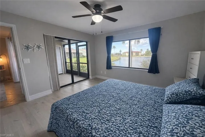 Bedroom with light wood-style flooring, access to exterior, ceiling fan, and a water view