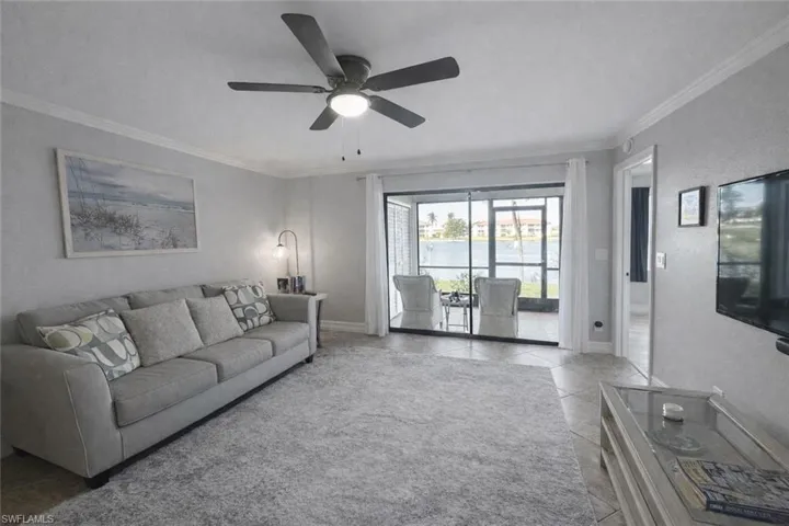 Living room featuring crown molding, ceiling fan, and light tile patterned floors