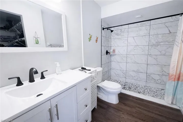 Bathroom featuring vanity, a stall shower, and dark wood-type flooring