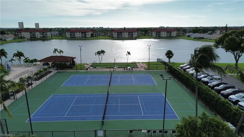 View of tennis court with a water view