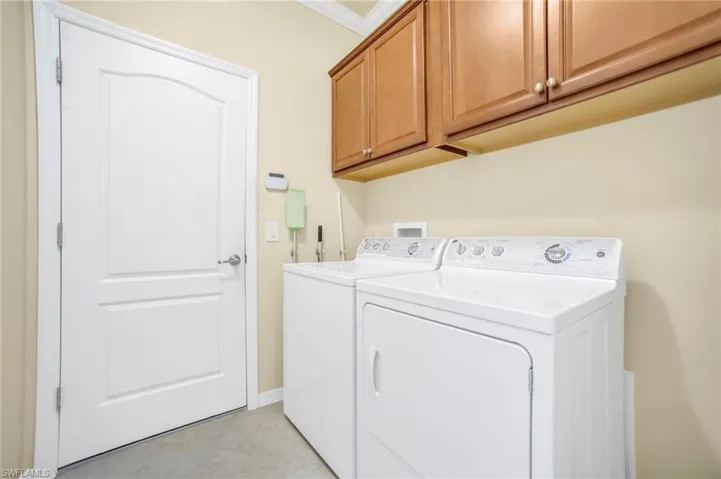 Laundry room featuring cabinet space, washer and dryer, and crown molding