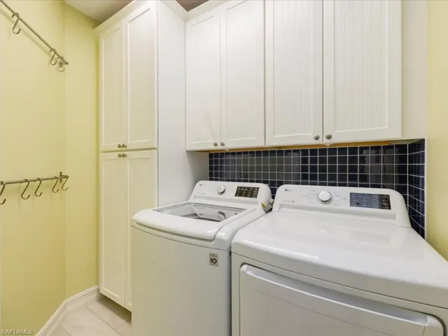 Laundry room with cabinet space, light tile patterned floors, and washing machine and clothes dryer