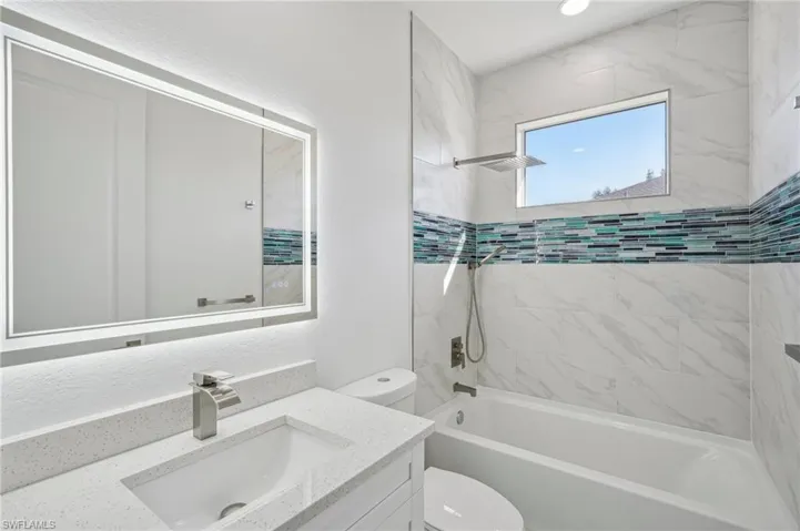 Full bathroom with tiled shower / bath, vanity, and toilet