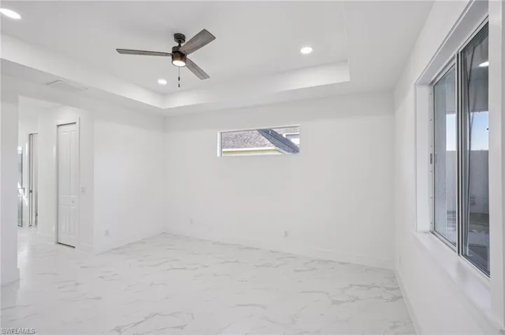 Spare room featuring a raised ceiling and ceiling fan