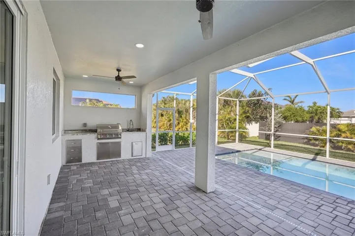 View of pool with an outdoor kitchen, area for grilling, a lanai, and sink