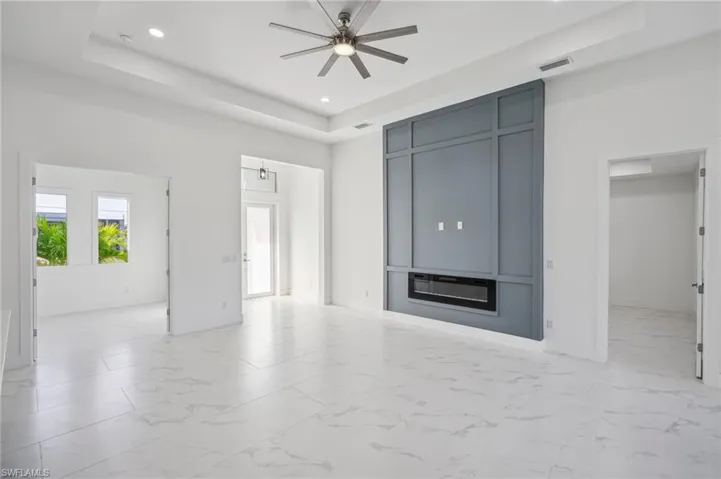 Unfurnished living room with a raised ceiling and ceiling fan