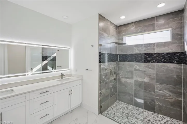 Bathroom featuring a tile shower and vanity