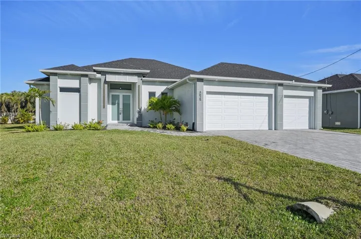 View of front of home with a garage, a front yard, and french doors