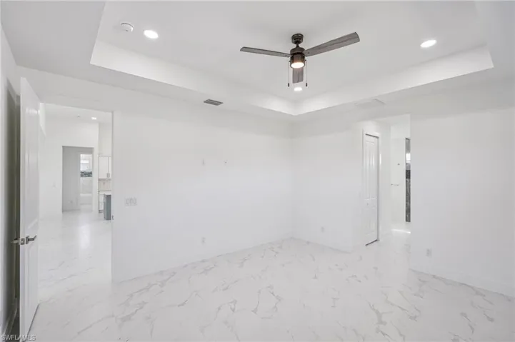 Unfurnished room featuring a raised ceiling and ceiling fan