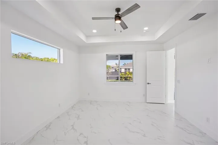 Unfurnished room featuring ceiling fan, a healthy amount of sunlight, and a raised ceiling