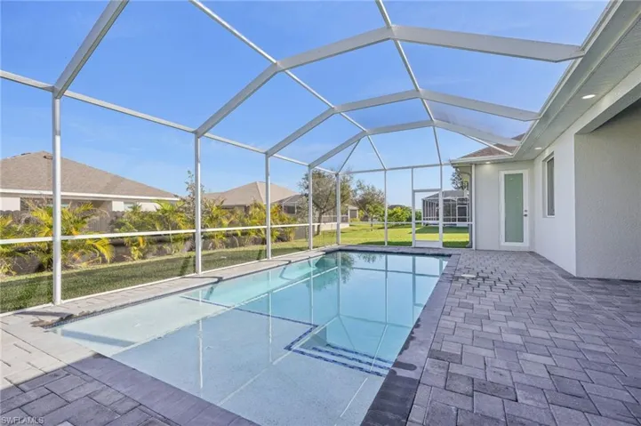 View of swimming pool featuring a yard, a patio, and glass enclosure