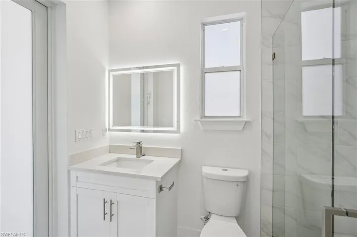 Bathroom featuring walk in shower, vanity, and toilet