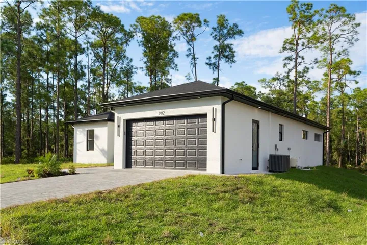 View of home's exterior featuring stucco siding, decorative driveway, an attached garage, and a lawn