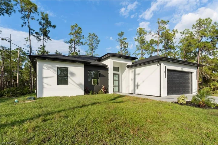 View of front facade with an attached garage, stucco siding, and a front lawn