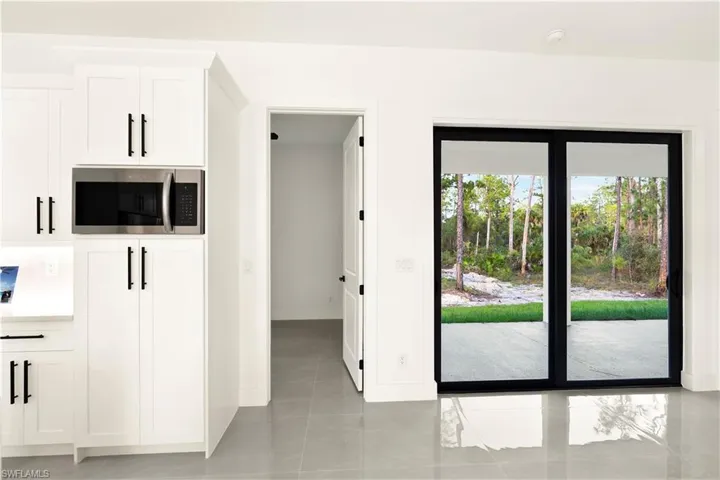 Kitchen with white cabinets, stainless steel microwave, light tile patterned floors, and light countertops
