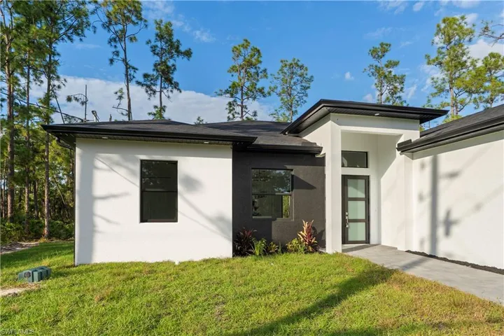 View of front of house with a front lawn and stucco siding
