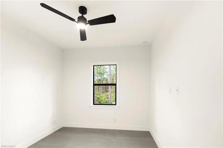Empty room with light tile patterned floors and a ceiling fan