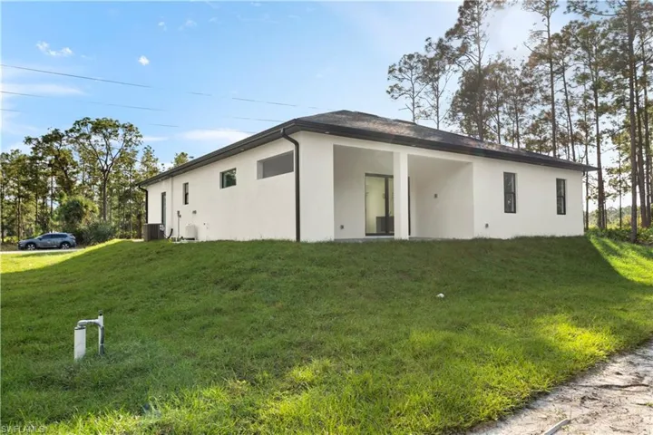 Back of house with stucco siding, a lawn, and a patio area