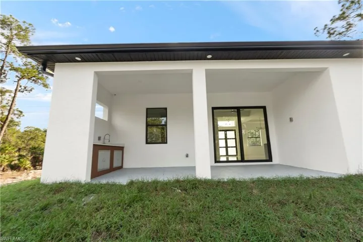 Rear view of house featuring a patio, stucco siding, and a yard