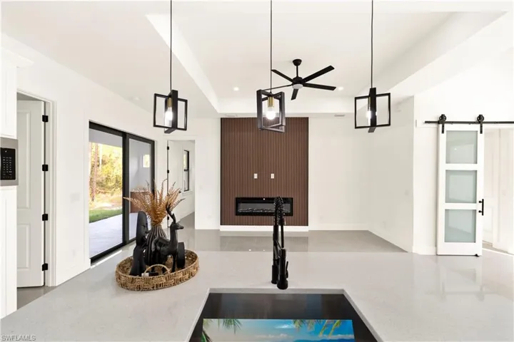 Kitchen featuring hanging light fixtures, a barn door, light stone counters, and recessed lighting