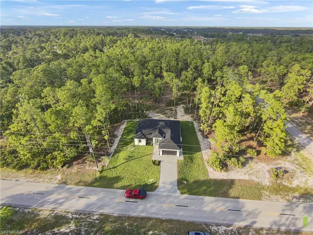 Aerial view of property and surrounding area featuring a forest