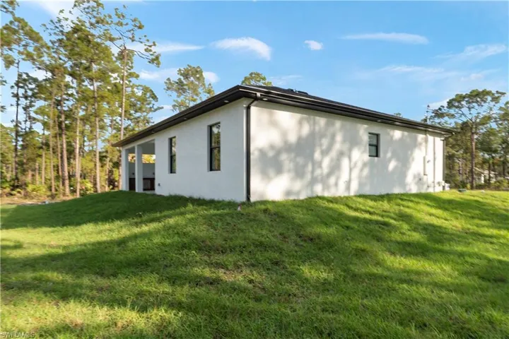 View of side of home with stucco siding and a lawn