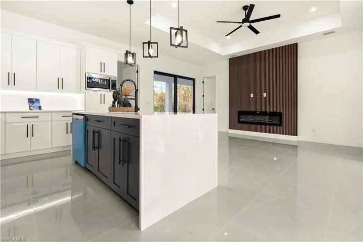 Kitchen with a tray ceiling, white cabinetry, pendant lighting, light stone countertops, and open floor plan