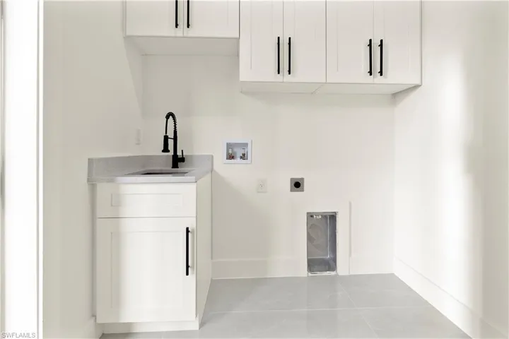 Washroom with cabinet space, light tile patterned floors, hookup for an electric dryer, and hookup for a washing machine