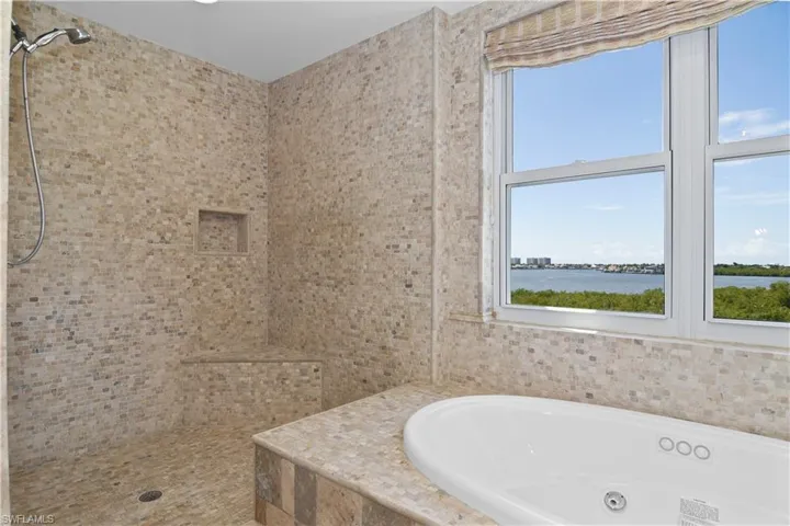 Bathroom with a water view, separate shower and tub, and a wealth of natural light