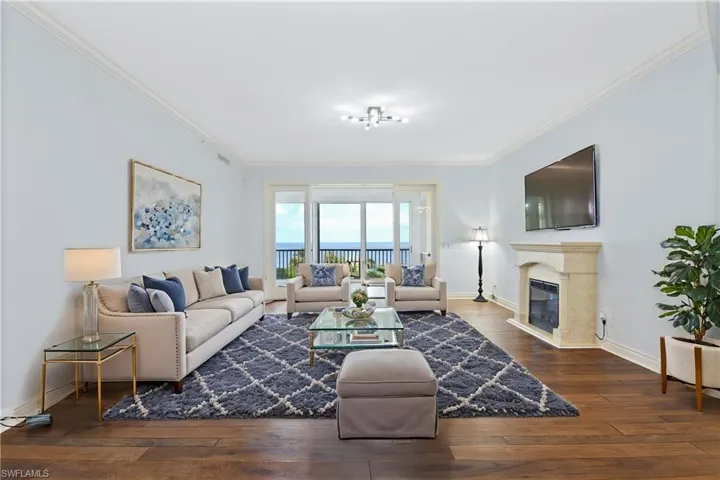 Living room featuring a fireplace, crown molding, and hardwood floors