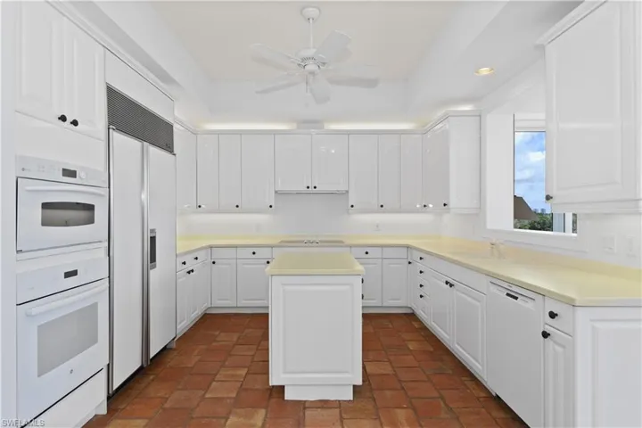 Kitchen featuring white cabinets, white appliances, sink, ceiling fan, and a kitchen island