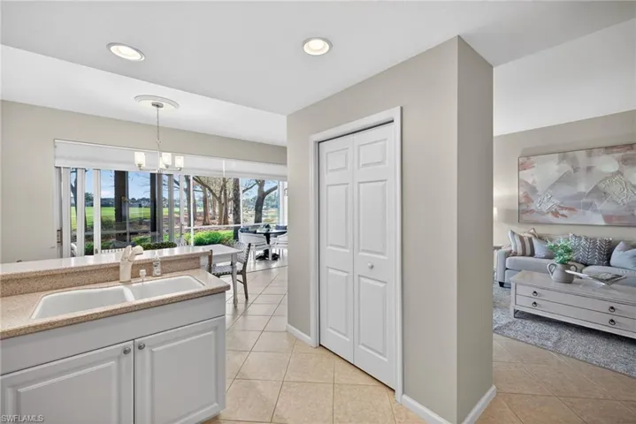 Kitchen featuring white cabinets, light tile patterned floors, a chandelier, and light stone counters